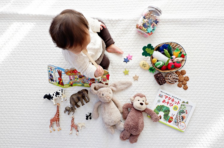girl sitting among a variety of toys